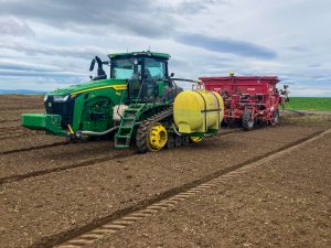 Kai behind the wheel of a tractor planting potatoes in Idaho