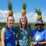 From left, Raven Kinnetz, Courtney Harle and Dr. Ebby Luvaga, economics, learn about pineapple production in Panama.