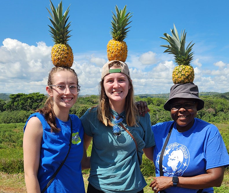 From left, Raven Kinnetz, Courtney Harle and Dr. Ebby Luvaga, economics, learn about pineapple production in Panama.
