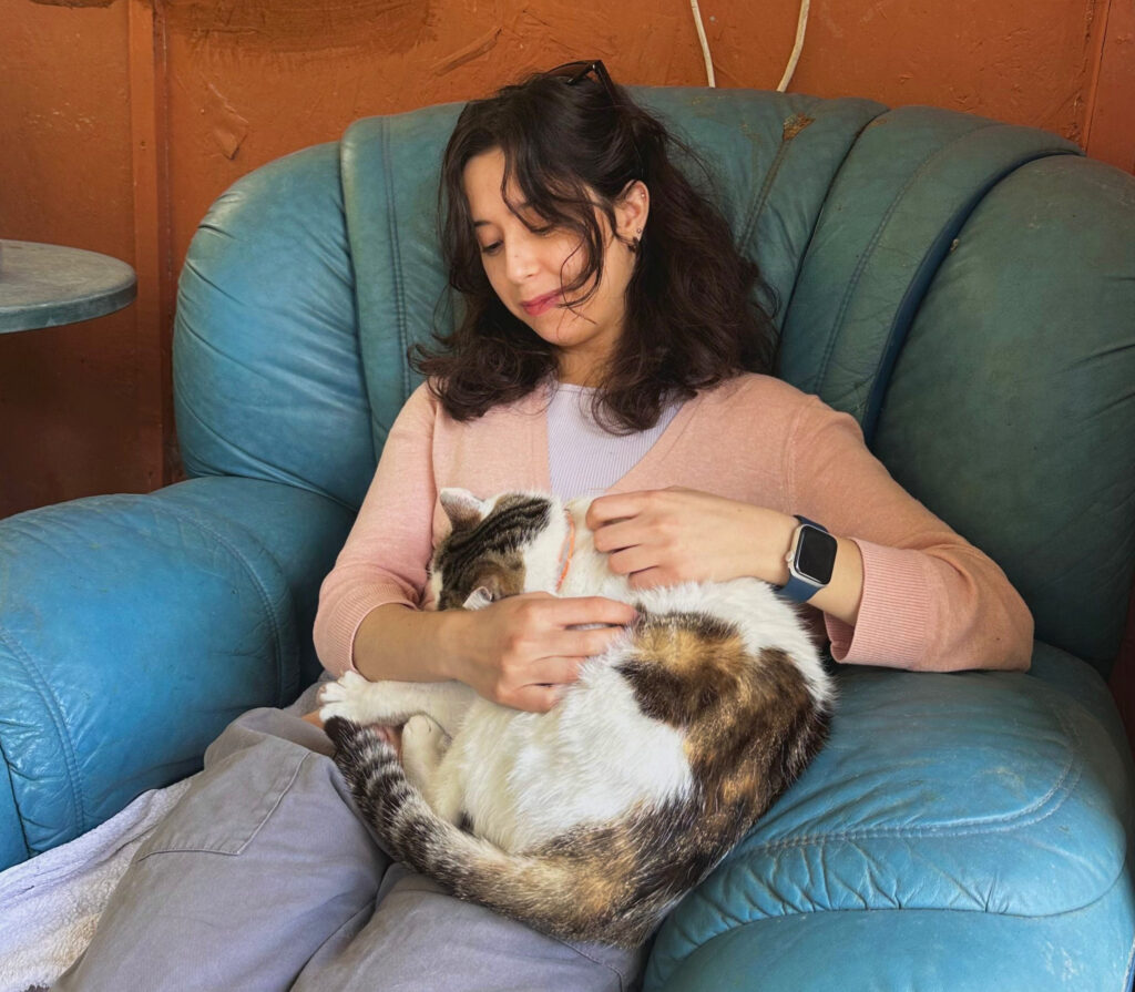 Nali Sanchez Carmona petting a sleepy cat at the Agios Neofytos CatPark in Cyprus.